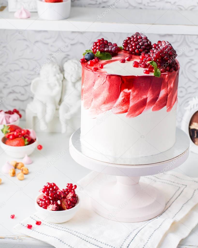 A beautiful chocolate cake with cheese cream, meringues, chocolate and fresh pomegranate on a light vintage background. Provence style. The original idea for a wedding cake or birthday cake.