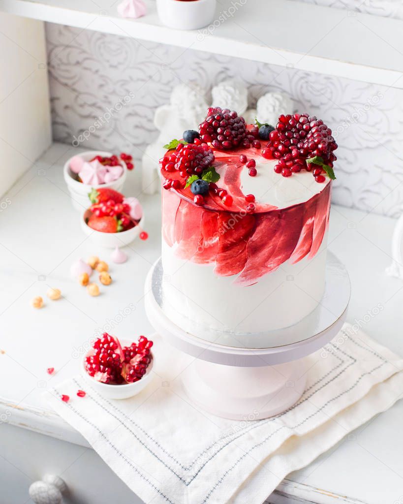 A beautiful chocolate cake with cheese cream, meringues, chocolate and fresh pomegranate on a light vintage background. Provence style. The original idea for a wedding cake or birthday cake.