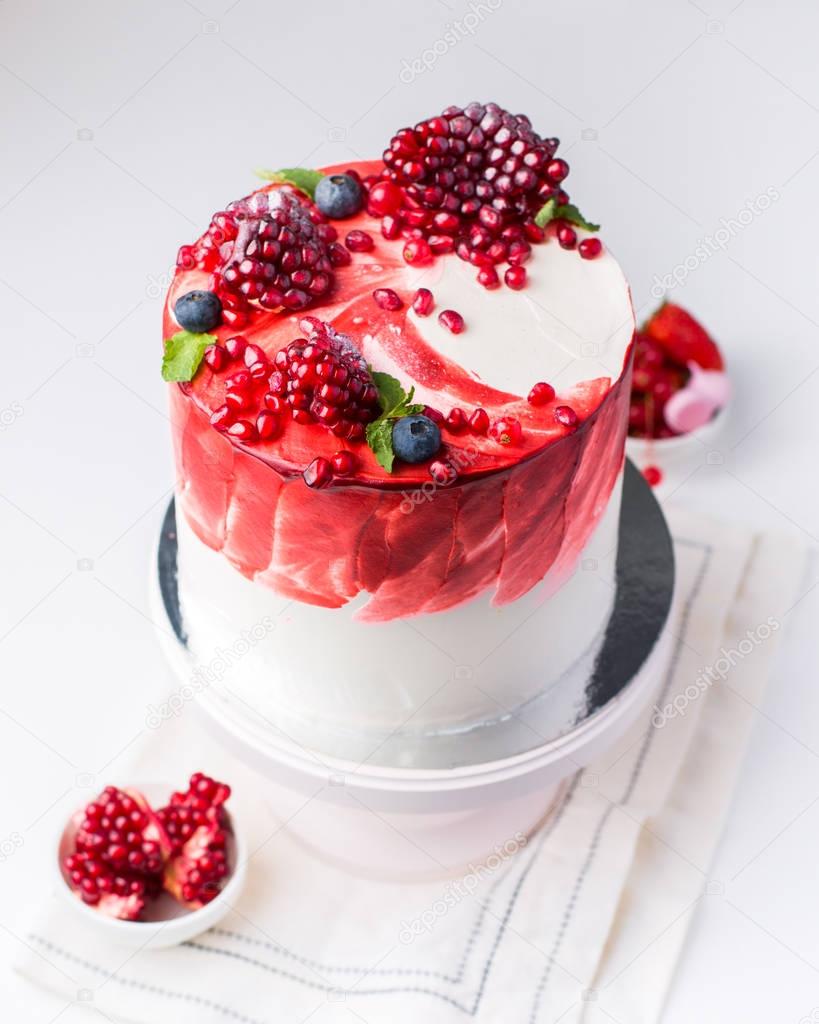 A beautiful chocolate cake with cheese cream, meringues, chocolate and fresh pomegranate on a light vintage background. Provence style. The original idea for a wedding cake or birthday cake.