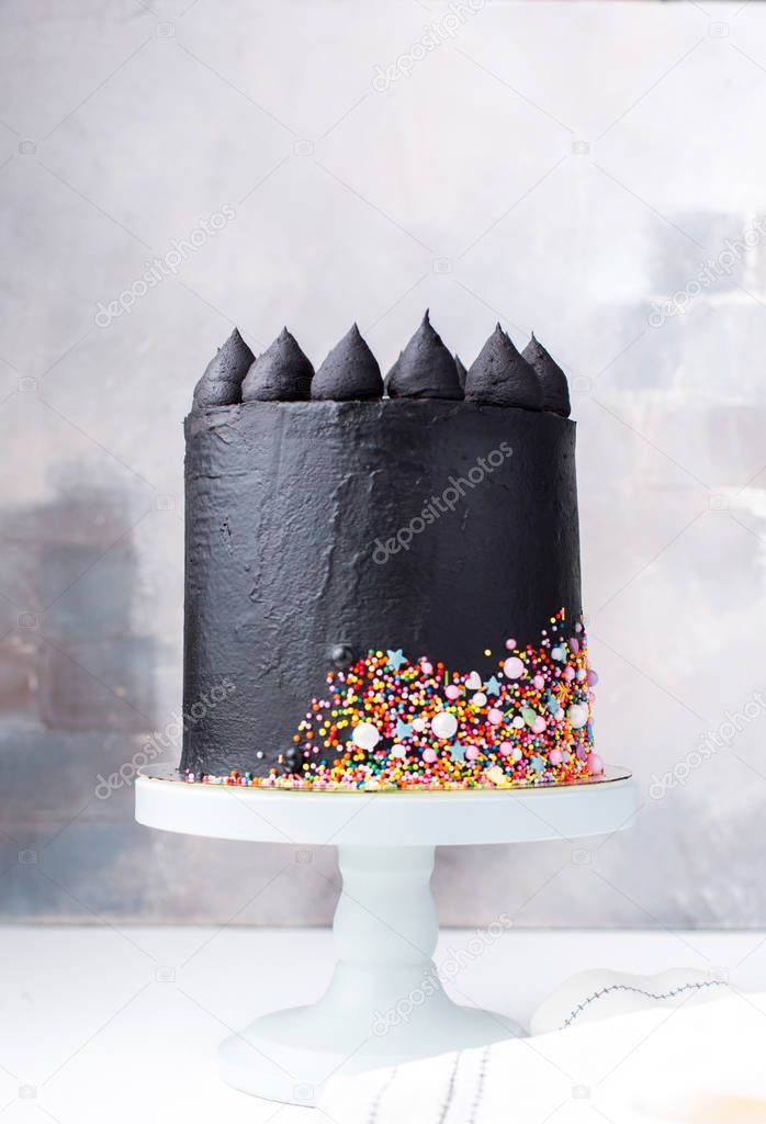 A beautiful black chocolate cake with cheese cream on a light vintage background. The original idea for a wedding cake or birthday cake.