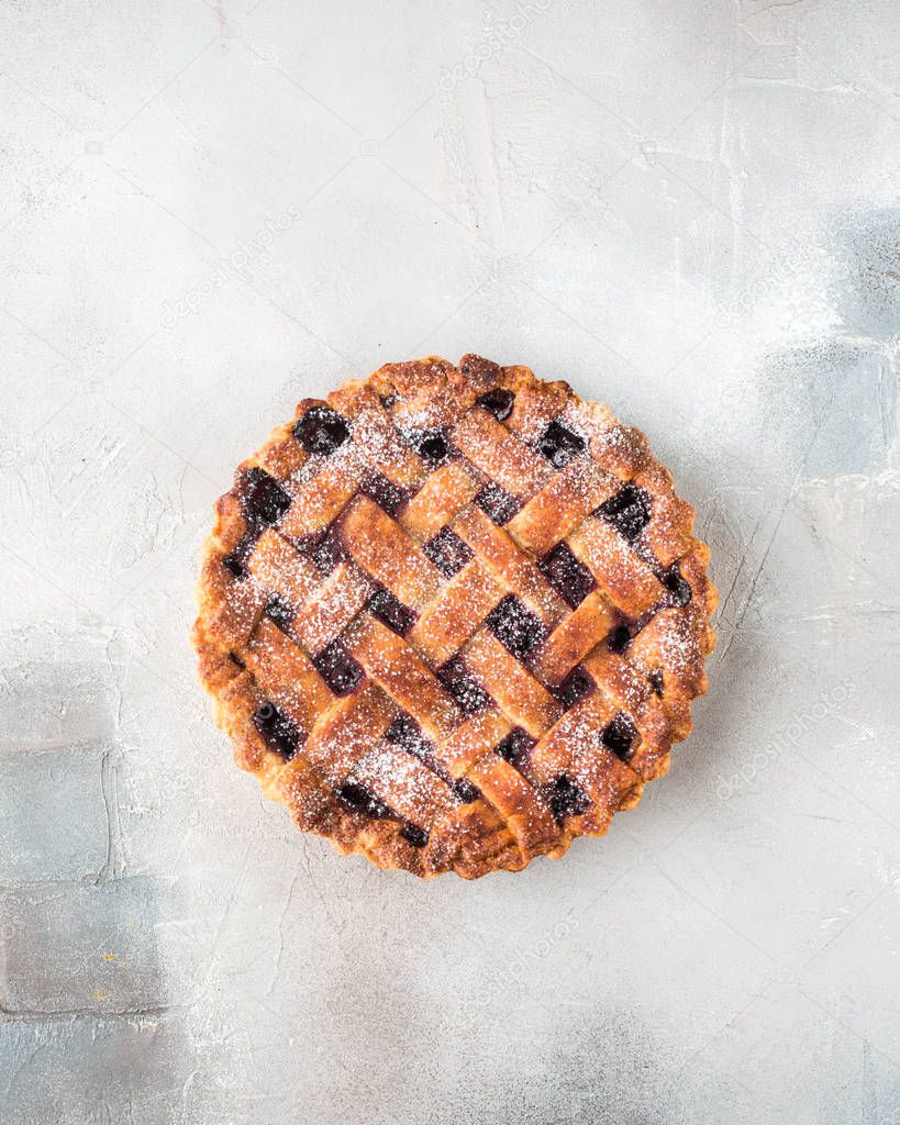 American cherry pie, powdered sugar on a gray concrete background. Copy Space. View blank space for text. Place for text. Food photo. Flat lay, top view Piece of cake in a wooden box. Craft Newspaper