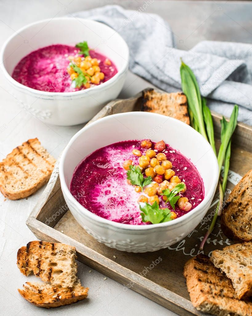 Beetroot cream soup with coconut milk, baked chickpeas, sesame, parsley on a gray concrete background. Baked chickpeas with spices. Useful dietary snack and lunch. Place for text. Flat lay, top view