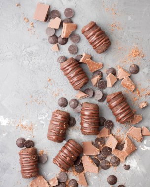 Bir sürü çikolata: çikolata şekerleme, çikolata barlar, çikolata damla... gri beton zemin üzerine. Çok tatlı arka plan.) Metin için yer. Düz yatıyordu, en iyi görünümü