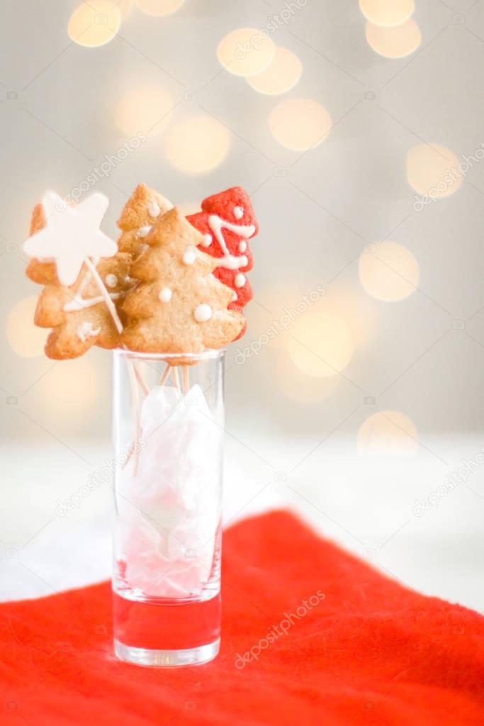 Christmas ginger cookies in the form of a Christmas tree and stars on a bright background with Christmas lights. Original Christmas card. Place for your text and congratulations