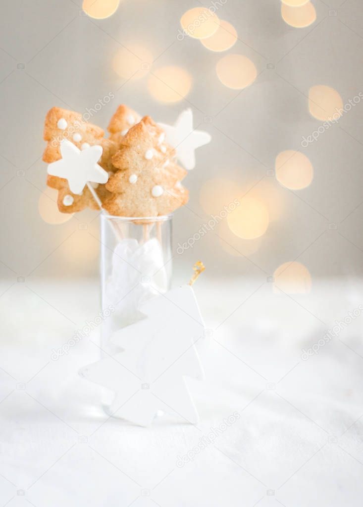 Christmas ginger cookies in the form of a Christmas tree and stars on a bright background with Christmas lights. Original Christmas card. Place for your text and congratulations