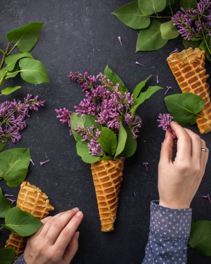 Dondurma külahı siyah bir beton zemin üzerine Lila dalları ile. Taze çiçekler. güzel bir buket çiçek. Uzay kopyalayın. Metin için boş alan görüntüleyin. Metin için yer. Gıda fotoğraf. Düz yatıyordu, en iyi görünümü
