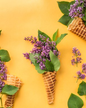 Dondurma külahı leylak dallarında parlak sarı bir arka plan ile. Taze çiçekler. güzel bir buket çiçek. Uzay kopyalayın. Metin için boş alan görüntüleyin. Metin için yer. Gıda fotoğraf. Düz yatıyordu, en iyi görünümü
