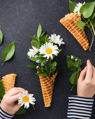 Dondurma külahı chamomiles siyah bir beton zemin üzerine buket. Taze çiçekler. kır çiçekleri güzel buket. Uzay kopyalayın. Metin için yer. Gıda Fotoğraf elleri olan. Düz yatıyordu, en iyi görünümü