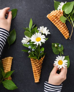 Dondurma külahı chamomiles siyah bir beton zemin üzerine buket. Taze çiçekler. kır çiçekleri güzel buket. Uzay kopyalayın. Metin için yer. Gıda Fotoğraf elleri olan. Düz yatıyordu, en iyi görünümü