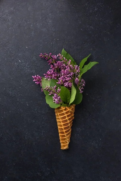 Dondurma külahı siyah bir beton zemin üzerine Lila dalları ile. Taze çiçekler. güzel bir buket çiçek. Uzay kopyalayın. Metin için boş alan görüntüleyin. Metin için yer. Gıda fotoğraf. Düz yatıyordu, en iyi görünümü