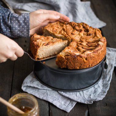 Ahşap arka plan üzerinde elma ile tam buğday unu ile ev yapımı kek. Elleriniz ve çiçekler gıda fotoğraf. Yararlı diyet pişirme.