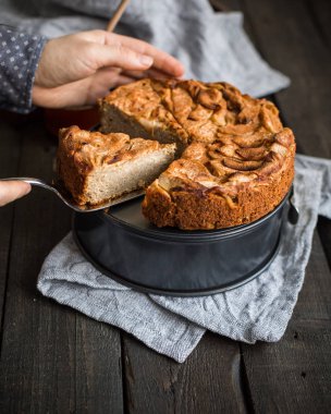 Ahşap arka plan üzerinde elma ile tam buğday unu ile ev yapımı kek. Elleriniz ve çiçekler gıda fotoğraf. Yararlı diyet pişirme.