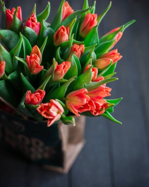 Bir kağıt torba koyu ahşap bir arka plan üzerinde kırmızı lale buketi. Bahar! Tazelik! Güzel bir buket çiçek. Metin için yer. Kartı orijinal arka plan veya kart. Vintage ülke rustik tarzı