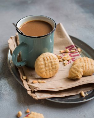 Kraft kağıt bir seramik vintage fincan kakao ile metal bir vintage tepsi üzerinde fıstıklı bisküvi.