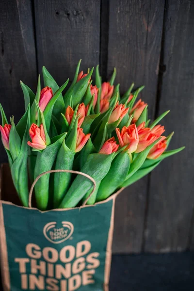 Bir kağıt torba koyu ahşap bir arka plan üzerinde kırmızı lale buketi. Bahar! Tazelik! Güzel bir buket çiçek. Metin için yer. Kartı orijinal arka plan veya kart. Vintage ülke rustik tarzı