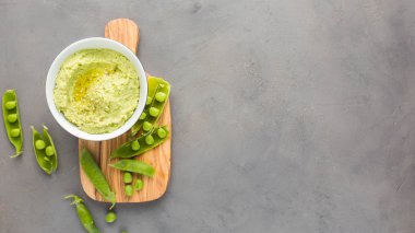 Nohut ve yeşil bezelye, zeytinyağı ve zeytin-ahşap panosunda baharat geleneksel klasik humus. Yararlı diyet çerez. 