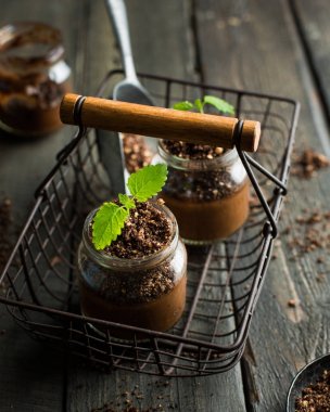 Vegan chocolate banana avocado mousse in a jar. A green sprout of mint grows from mousse. An unusual original serving of a tasty useful dessert.  clipart