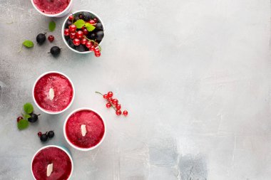 Berry smoothies bir ışık gri beton zemin üzerine taze kırmızı kuş üzümü ve metin için siyah gooseberry.place parlak kağıt bardak dondurulmuş. düz yatıyordu, en iyi görünümü