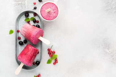 Berry smoothies bir ışık gri beton zemin üzerine taze kırmızı kuş üzümü ve metin için siyah gooseberry.place parlak kağıt bardak dondurulmuş. düz yatıyordu, en iyi görünümü