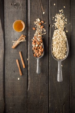 Natural products in iron vintage scoops on wooden granary boards. Hercules flakes (oat flakes), sunflower seeds, fresh peanuts, hazelnuts, honey. Ingredients for granola or oatmeal. Useful breakfast. clipart