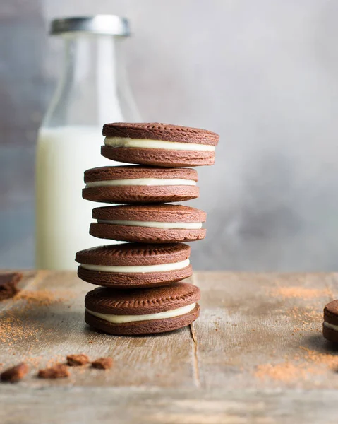 Chocolate cookies with cream. Traditional American popular homemade cookies. A stack of cookies on a wooden background with a bottle of milk.