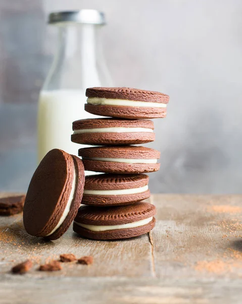 Chocolate cookies with cream. Traditional American popular homemade cookies. A stack of cookies on a wooden background with a bottle of milk.