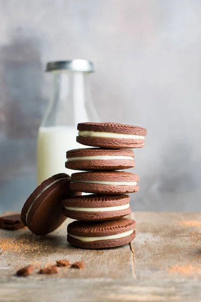 Chocolate cookies with cream. Traditional American popular homemade cookies. A stack of cookies on a wooden background with a bottle of milk.