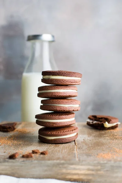 Chocolate cookies with cream. Traditional American popular homemade cookies. A stack of cookies on a wooden background with a bottle of milk.