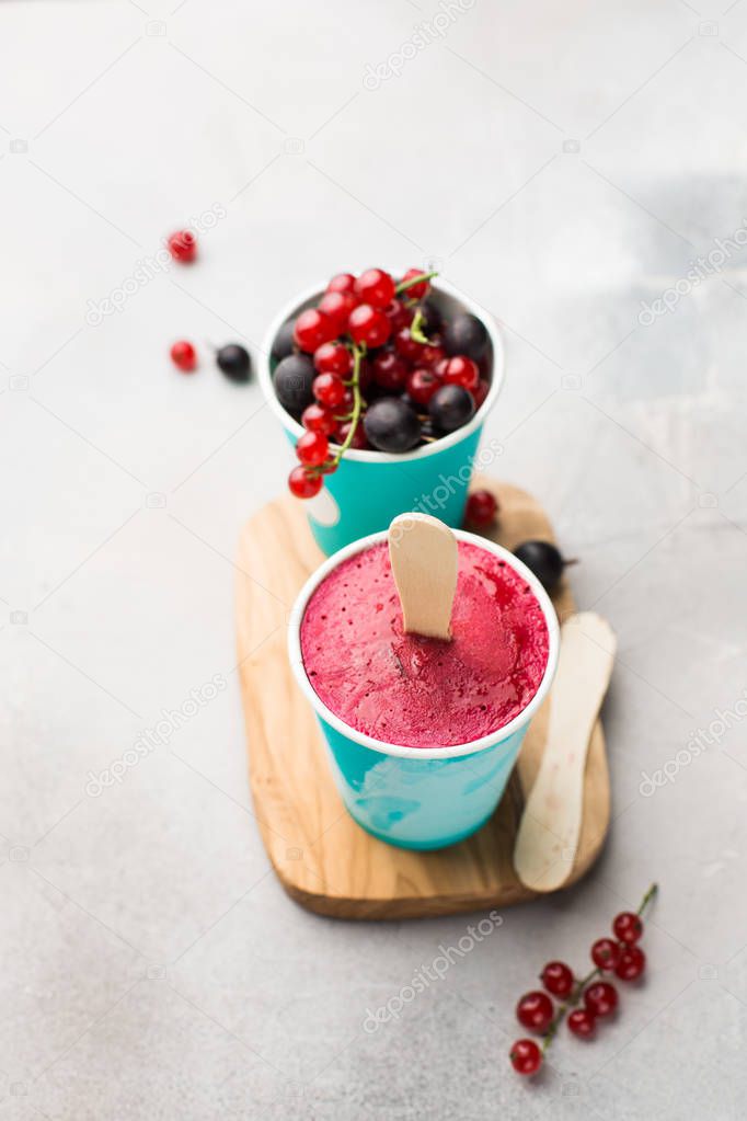 Frozen berry smoothies in bright paper cups on a light gray concrete background with fresh red currant and black gooseberry.place for text. flat lay, top view