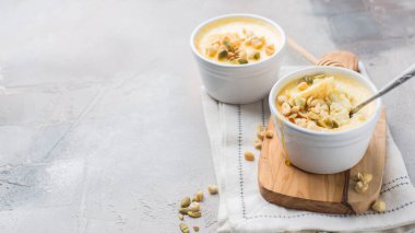 Klasik cheesecake ile fındık ve açık renkli beton ve ahşap tahta küçük seramik kavanozlarda tatlım. En lezzetli tatlı veya mükemmel sağlıklı kahvaltı!)