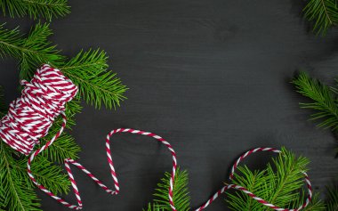 Noel ağacı ve kırmızı-beyaz dize (sicim) koyu ahşap arka plan üzerinde. Kış tatil kavramı. Düz yatıyordu, en iyi görünüm. Xmas sınır - yatay banner. Web boyutu. 
