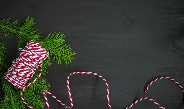 Noel ağacı ve kırmızı-beyaz dize (sicim) koyu ahşap arka plan üzerinde. Kış tatil kavramı. Düz yatıyordu, en iyi görünüm. Xmas sınır - yatay banner. Web boyutu. 