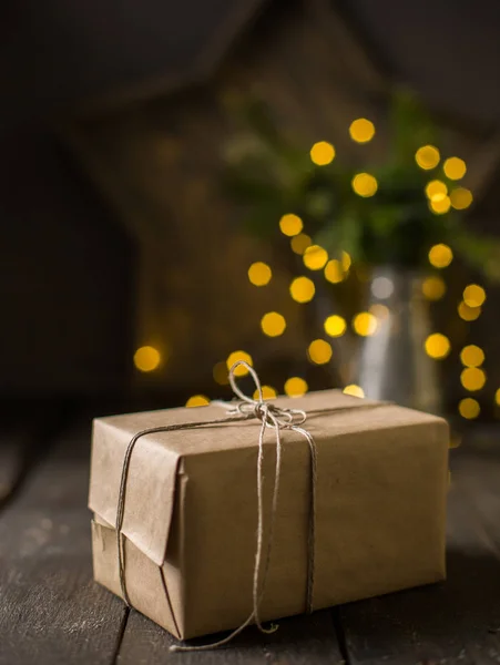 Christmas gift mood!) Gift wrapped in kraft paper on dark background lights. The best celebration background. Winter xmas holidays concept.