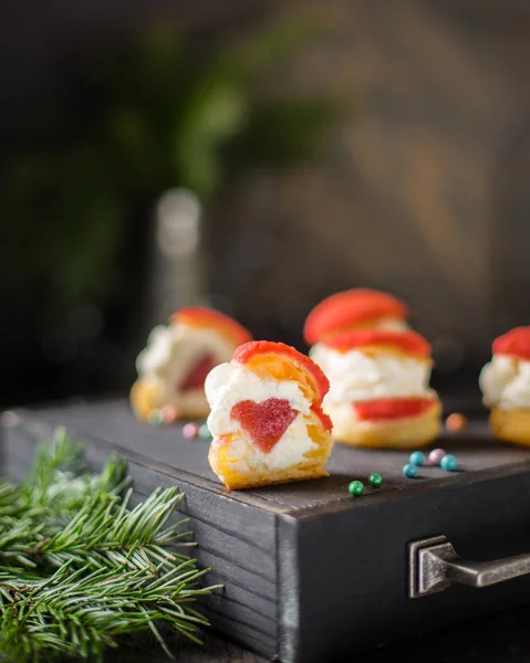 Choux! Peynirli kek krem ve çilekli jöle içinde kalp ışıkları karanlık bir ahşap zemin üzerine. Mükemmel bir Noel tatlı. En iyi kutlama arka plan. Kış xmas tatil kavramı.