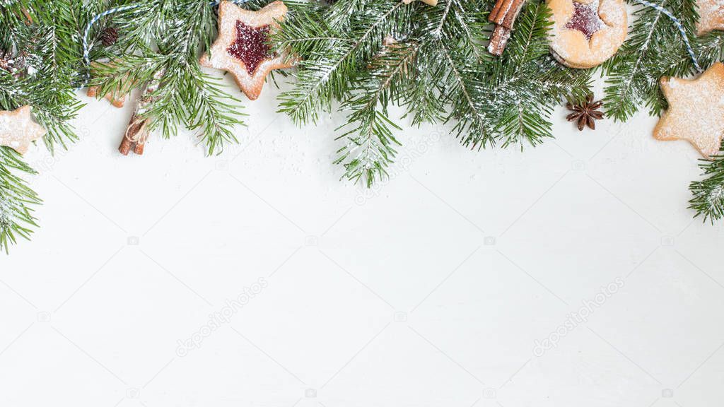 Ginger homemade cookies with strawberry jam on white wooden background with Christmas tree. Winter holidays concept. Flat lay, top view. Xmas Border - horizontal banner. Web size. 