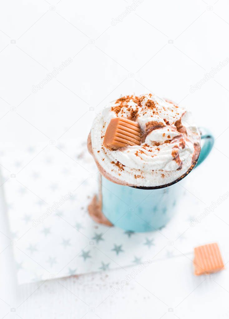 Christmas mood!) Hot chocolate with cream, cinnamon and a toffee in a blue vintage mug on a light background. The best celebration background. Winter xmas holidays concept.