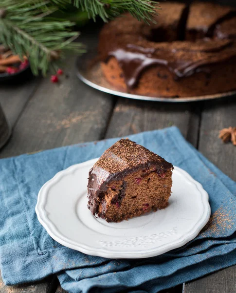 Fındık, kızılcık, çikolata ganache ve köknar ağacı ve baharat koyu ahşap zemin üzerine kakao tozu ile çikolatalı kek parçası. Noel dekor tablo. Kış xmas tatil kavramı. 