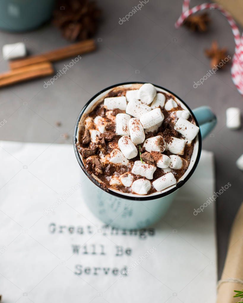 Great things will be served!) Mug of hot chocolate with marshmallow, cinnamon and milk on a gray concrete background with a Christmas tree and gifts. Winter xmas holidays concept. Festive mood.)