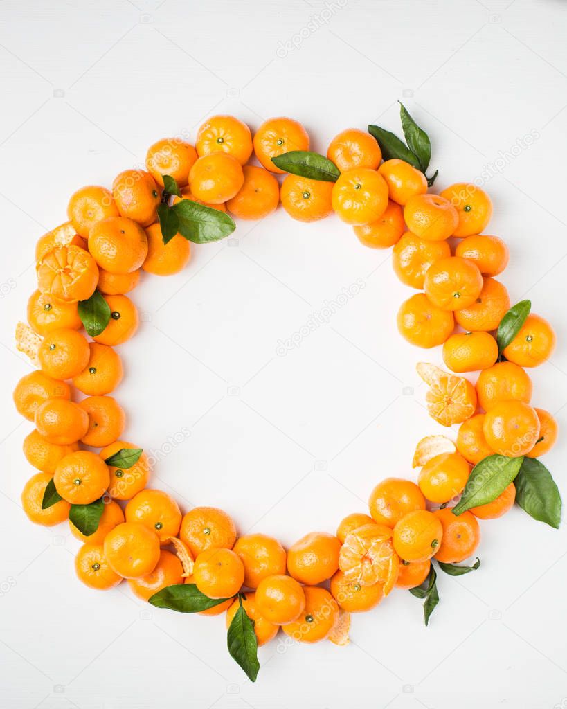 Christmas  tangerine mood!) Wreath made of  fresh small tangerines and green leaves on white wooden background. The best xmas celebration background.  Flat lay, top view, copy space. 