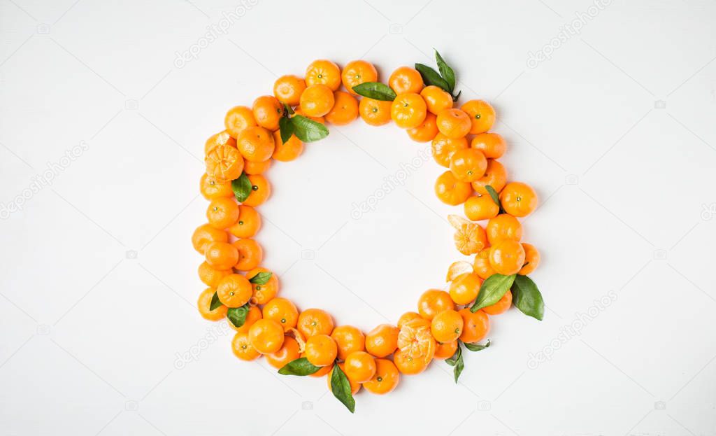 Christmas  tangerine mood!) Wreath made of  fresh small tangerines and green leaves on white wooden background. The best xmas celebration background.  Flat lay, top view, copy space. 