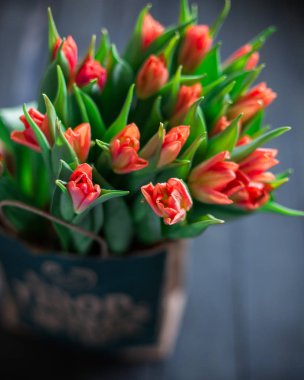 Bir kağıt torba koyu ahşap bir arka plan üzerinde kırmızı lale buketi. Bahar! Tazelik! Güzel bir buket çiçek. Metin için yer. Kartı orijinal arka plan veya kart. Vintage ülke rustik tarzı