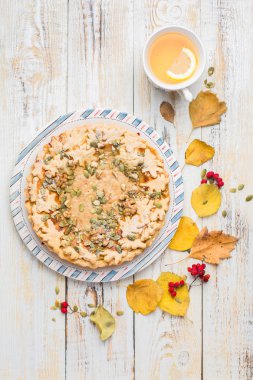 Kabak pasta, sıcak çay, sararmış yapraklar, kitap ve halı ile sonbahar arka plan. Mükemmel güneşli sonbahar. Ahşap açık beyaz sonbahar arka planı sizin için. Uzay kopyalayın. Metin için yer. Düz yatıyordu, en iyi görünümü