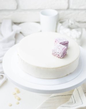 Bir kafede marshmallow ile kremsi beyaz mousse kek fotoğraf. Kesilmiş bir parça ile modern bir pasta. Açık renkli, beyaz tuğla duvar, hafif yemekler ve kek standı. Kahve evinin atmosferini. 