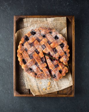 Amerikan vişneli tart, pudra şekeri gri beton zemin üzerine. Uzay kopyalayın. Metin için boş alan görüntüleyin. Metin için yer. Gıda fotoğraf. Düz yatıyordu, en iyi görünüm çok kolay mezarda. Zanaat gazete