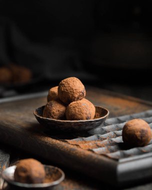 Çikolatalı trüf. Koyu renkli ahşap bir arka planda kakao serpiştirilmiş koyu çikolata ve vişne şekeri. Atmosferik yemek fotoğrafı. Ev yapımı taze enerji topları..