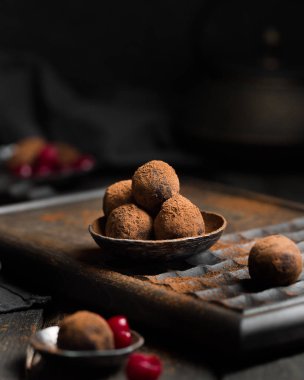 Çikolatalı trüf. Koyu renkli ahşap bir arka planda kakao serpiştirilmiş koyu çikolata ve vişne şekeri. Atmosferik yemek fotoğrafı. Ev yapımı taze enerji topları..