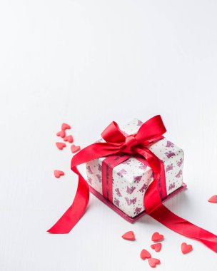 Kırmızı kurdeleli hediye kutusu ve siyah beton zeminde şeker kalpler. Güzel Sevgililer Günü. Romantik bir ruh hali..) 