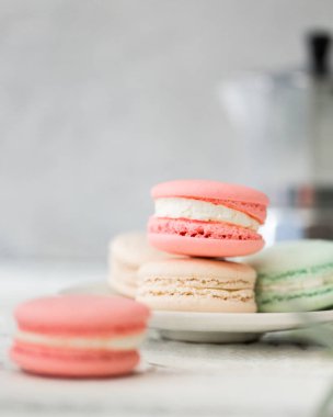 Beyaz tabak kopya alanı için arka plan ile ahşap masa koymak renkli Fransızca veya İtalyanca macarons yığını. Tatlı için öğleden sonra çay veya kahve molası ile servis. Güzel yemek arka plan boş.