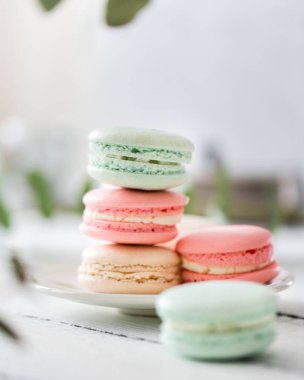 Beyaz tabak kopya alanı için arka plan ile ahşap masa koymak renkli Fransızca veya İtalyanca macarons yığını. Tatlı için öğleden sonra çay veya kahve molası ile servis. Güzel yemek arka plan boş.