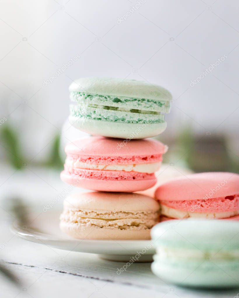 Colorful French or Italian macarons stack on white plate put on wood table with copy space for background. Dessert for served with afternoon tea or coffee break.Beautiful meal background with blank.